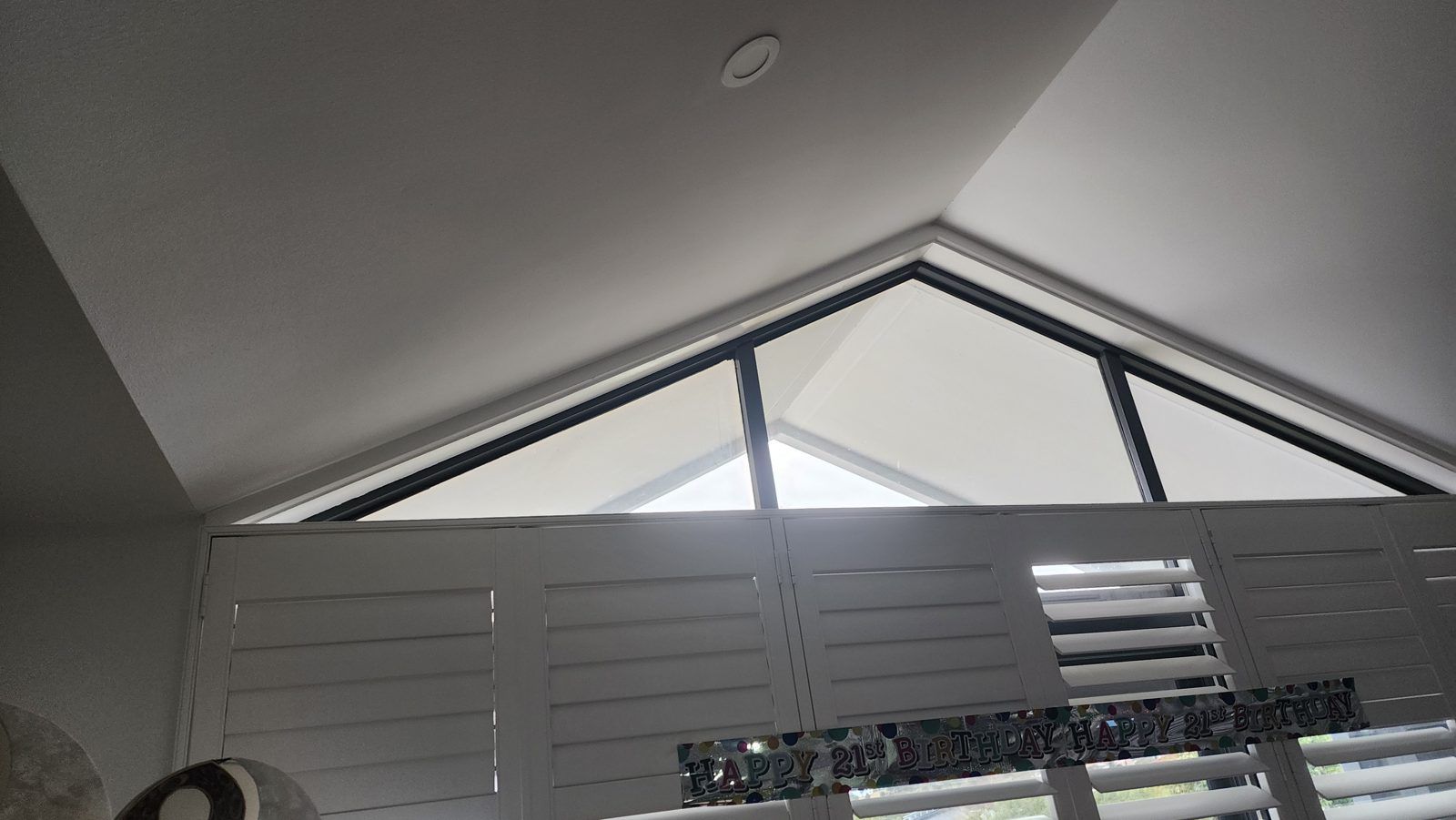 Raked cathedral ceiling windows finished with custom-shaped shutters