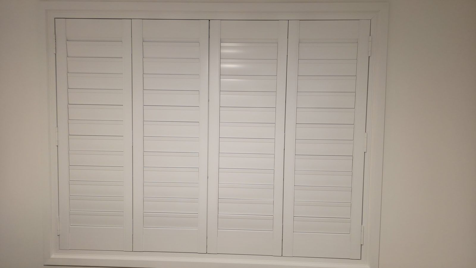 Bedroom window neatly finished with white plantation shutters