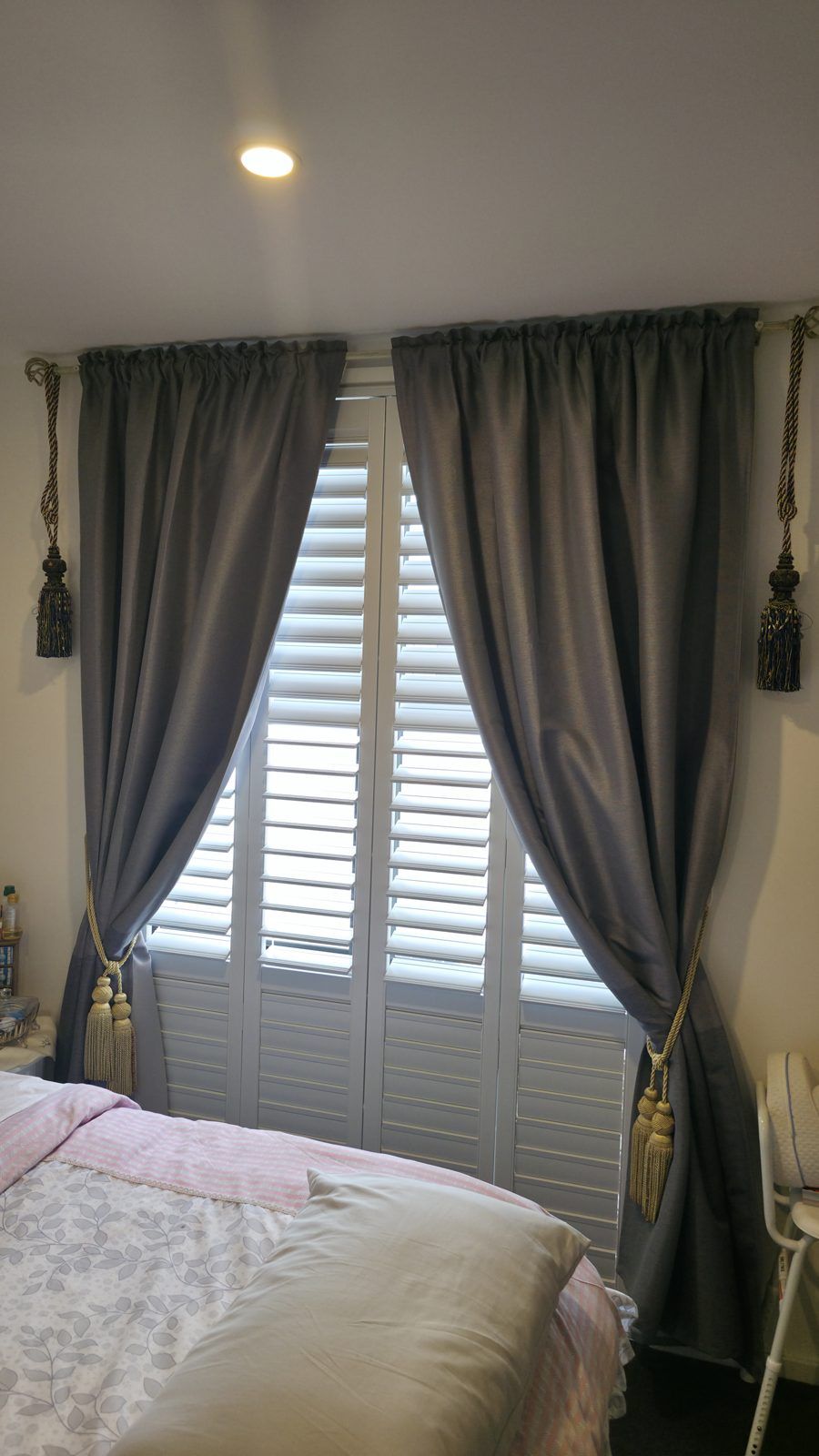 Bedroom window with plantation shutters layered behind full-length curtains